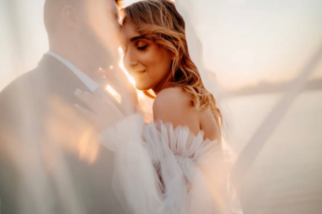 Romantic golden hour portrait of couple in white with dreamy lighting
