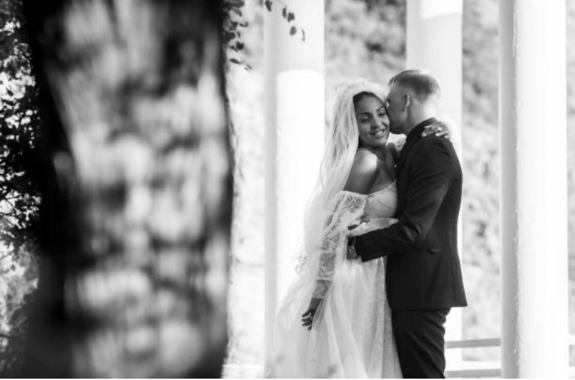 Black and white intimate portrait of couple under ivy-covered archway